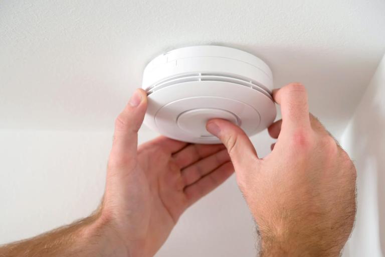 Hands testing a smoke alarm battery